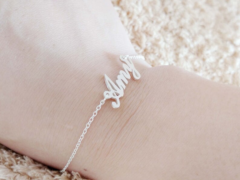 May include: A silver chain bracelet with the name "Amy" spelled out in cursive.