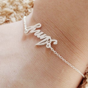 May include: A silver bracelet with the word "Hugs" written in cursive.