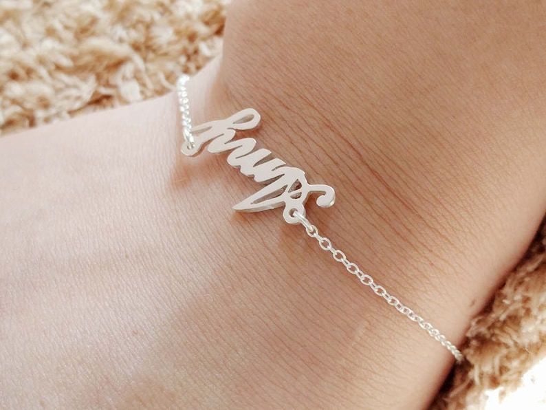 May include: A silver bracelet with the word "Hugs" written in cursive.
