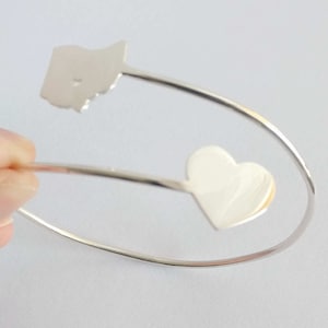 Peut inclure: Bracelet en argent avec un cœur et un charme en forme d'état.