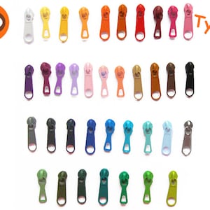 Könnte beinhalten: Sortiment von 36 bunten Reißverschluss-Zierbändern in verschiedenen Farben, darunter Rot, Blau, Grün, Gelb, Orange, Lila, Rosa und Schwarz. Die Reißverschluss-Zierbänder sind in Reihen von 8 angeordnet. Der Text "Typ 2" ist in der oberen rechten Ecke des Bildes sichtbar.
