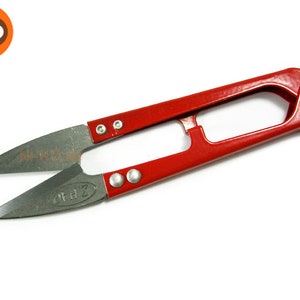 Pode incluir: Tesoura de fio de metal vermelho com lâmina prateada. A tesoura tem um pequeno furo na alça para pendurar.