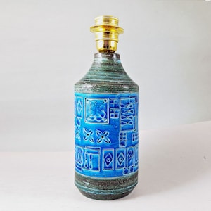 May include: A blue and green ceramic table lamp with a geometric pattern. The lamp has a brass base and a white cord.