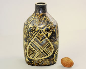 May include: A dark gray ceramic vase with a yellow geometric design. The vase has a rounded body and a narrow neck.