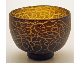 May include: A brown coconut bowl with a natural wood grain pattern. The bowl is made by Kosta Boda, since 1942.