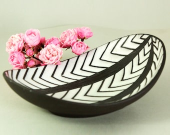 May include: A black ceramic serving dish with a white chevron pattern. The dish is shaped like a leaf and is perfect for serving snacks or appetizers.