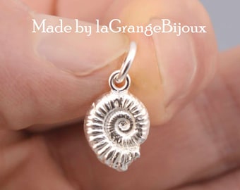 Pode incluir: Charme de prata em forma de fóssil de amonite. O charme tem aproximadamente 2,5 cm de diâmetro e apresenta um design detalhado.