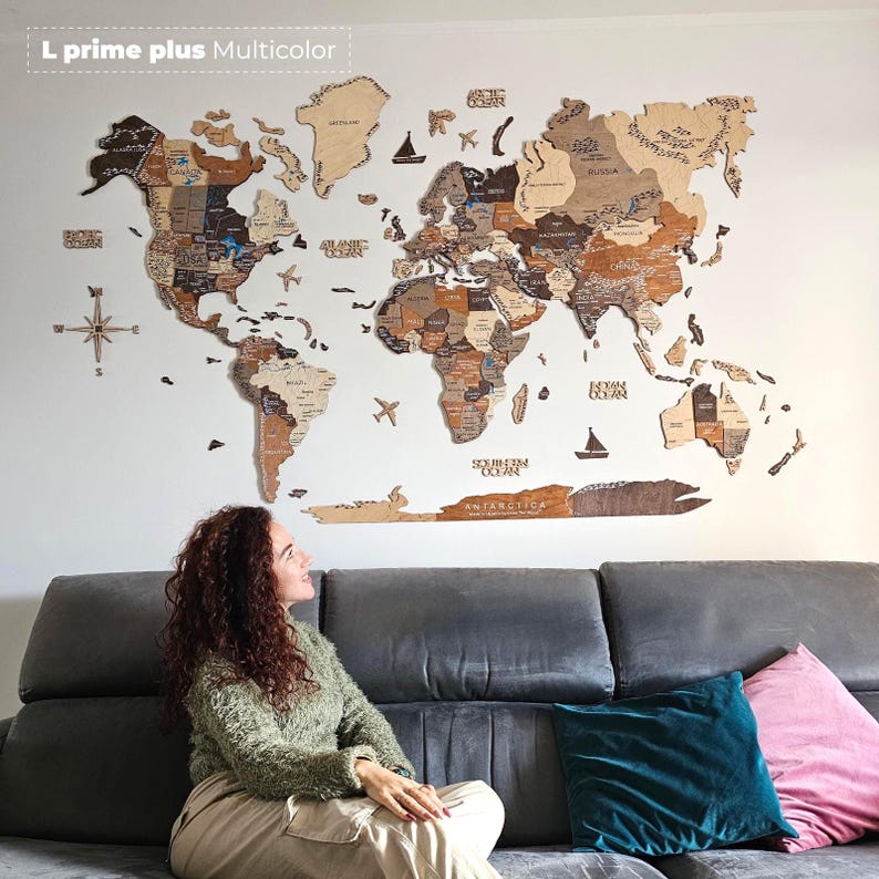 Pu&ograve; includere: Una grande mappa del mondo in legno multicolore montata su una parete bianca. La mappa presenta i contorni dettagliati dei paesi ed &egrave; decorata con piccoli aerei e barche di legno. Il testo "L prime plus Multicolor" &egrave; nell'angolo in alto a sinistra.