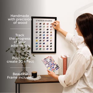 May include: A framed United States flags map with push pins for tracking travel. The black frame surrounds a print of state flags. The text on the frame reads "UNITED STATES". The image also includes the text "Handmade with precision of wood".