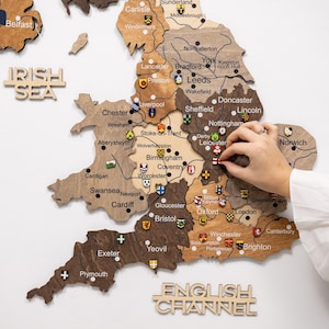 May include: A detailed wooden map of England, featuring city names and decorative pins. The map is crafted from various shades of brown wood. The words "IRISH SEA" and "ENGLISH CHANNEL" are also visible.