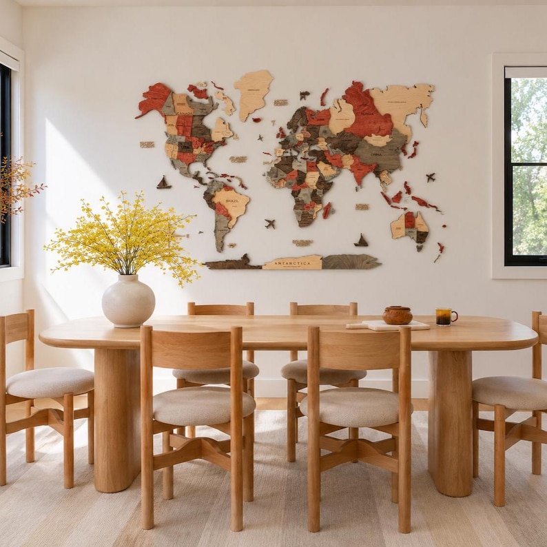 May include: A large, multi-layered wooden world map wall art piece featuring continents in shades of red, brown, and natural wood tones. The map includes small wooden icons of ships and airplanes scattered across the oceans and a label for Antarctica.
