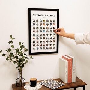 May include: A white ceramic mug with a black handle and the text "But First, Coffee" in a bold, black font. The mug is set against a blurred background, suggesting a cozy setting.