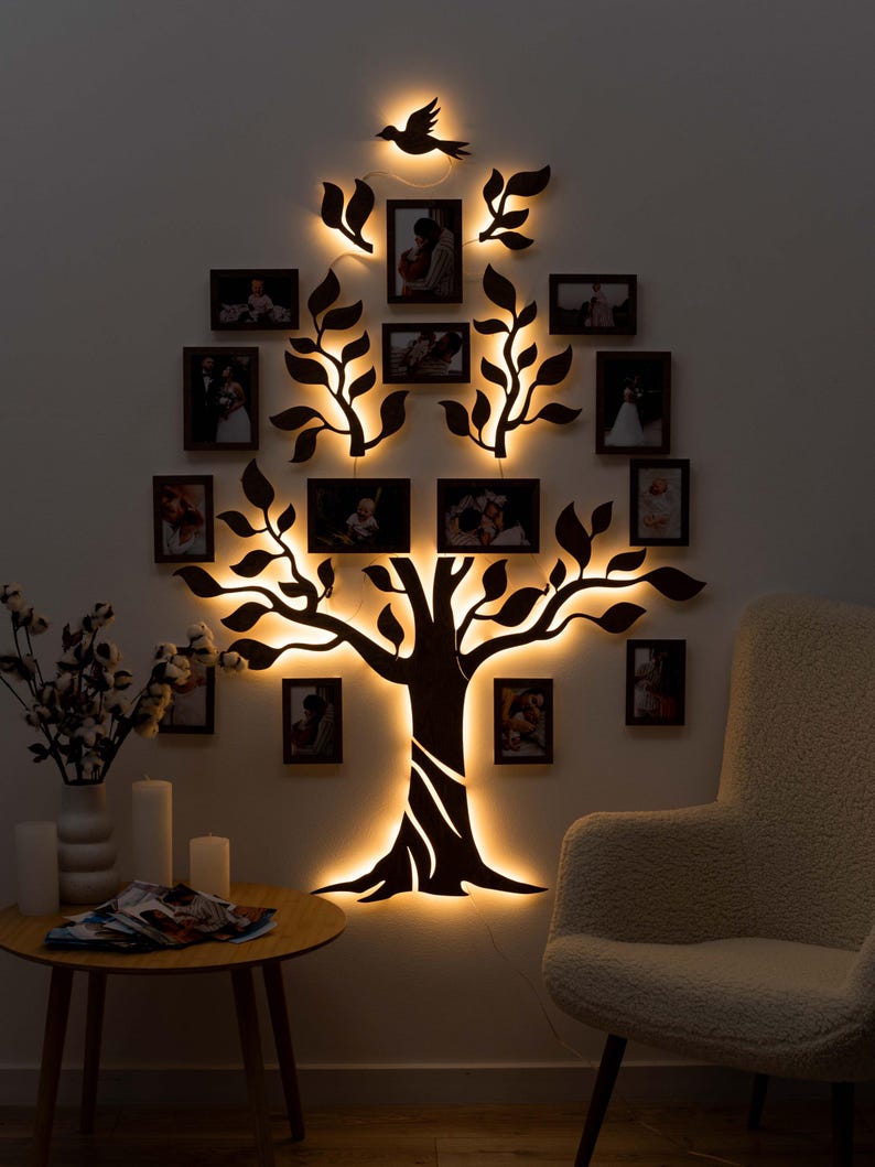 Puede incluir: Una silueta negra de un &aacute;rbol con ramas y hojas, iluminada con luces LED blancas c&aacute;lidas. El &aacute;rbol est&aacute; decorado con m&uacute;ltiples marcos de fotos negros, cada uno con una foto diferente. Una silueta de p&aacute;jaro est&aacute; posada en una rama en la parte superior del &aacute;rbol.