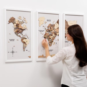 Peut inclure: Trois cartes du monde en bois encadrées dans des cadres blancs. Les cartes sont faites de différentes nuances de bois et comportent des épingles marquant des lieux. Les cartes sont étiquetées avec les noms des océans et une rose des vents.