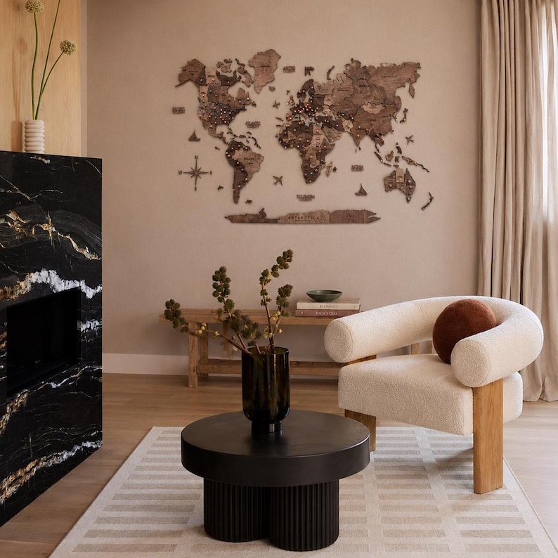 May include: A large, multi-piece wooden world map wall art installation featuring dark brown continents, islands, and a compass rose. The map includes detailed country borders and labels, mounted directly onto a plain, light-colored interior wall.
