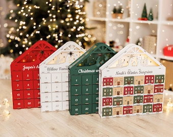 May include: Four wooden advent calendars in red, white, green, and white, shaped like houses. Each calendar has numbered doors for December. The calendars are decorated with Christmas-themed cutouts and text, including "Jasper's A", "Willow Famil", "Christmas w", and "Noah's Winter Surprises".