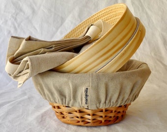 May include: A beige linen bread basket with a wooden lid and a label that reads "marianela".