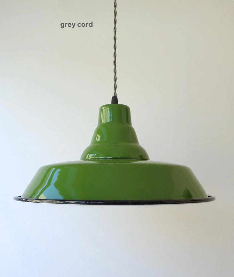 May include: A glossy green pendant light fixture with a wide, flared shade and a smooth, rounded top section. The lamp is suspended by a twisted grey cord. The bottom edge of the shade features a thin, dark rim, and the text grey cord is visible.