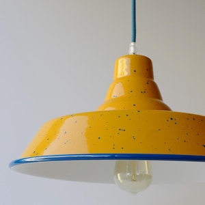 May include: A yellow pendant light with a glossy finish and blue speckles, featuring a blue rim and a clear light bulb. The fixture is suspended by a petrol blue cord. The text "petrol blue cord" is visible in the upper left corner of the image.