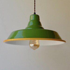 May include: A green pendant light with a glossy finish, a yellow rim, and a white interior. The fixture hangs from a brown cord and includes a single exposed Edison-style light bulb. The text brown cord is visible in the upper left corner.
