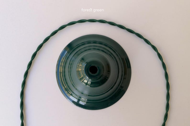 May include: A forest green circular lamp shade base with a central opening, accompanied by a matching forest green twisted fabric electrical cord that curves around the base. The text "forest green" is printed above the lamp shade component.