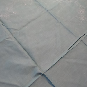 May include: A light blue tablecloth with a white embroidered floral design. The tablecloth is folded in half, creating a diamond shape.