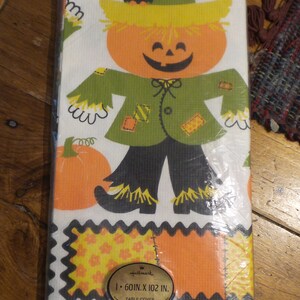 Puede incluir: Un mantel vintage de Hallmark con un espantapájaros de calabaza sonriente con un pájaro negro en su sombrero. El mantel mide 152,4 cm x 259,1 cm y está empaquetado en plástico. El mantel es naranja, verde, amarillo y negro.