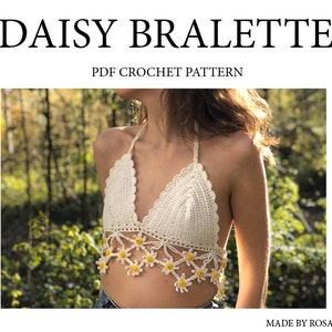 Puede incluir: Un bralet de crochet blanco con un diseño de margarita. El bralet tiene un estilo de cuello halter y está hecho con hilo blanco. El bralet se muestra en una modelo en un entorno de bosque. El texto "DAISY BRALETTE" y "PDF CROCHET PATTERN" se muestra arriba de la imagen. El texto "MADE BY ROSALYECROCHET" se muestra debajo de la imagen.