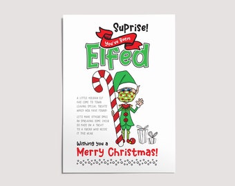 Op de afbeelding: Een kerstkaart met een cartoon-elf die een mondkapje draagt en een snoepstok vasthoudt. De kaart zegt "Suprise! You've Been Elfed" en "Wishing you a Merry Christmas!"