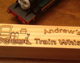 May include: A wooden train whistle with an engraved image of a train and the text "Andrew's Train Whistle".
