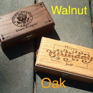 May include: Two wooden boxes with engraved designs. The top box is walnut and has a United States Army emblem with the text 'Dusty Rodgers' underneath. The bottom box is oak and has the text 'Happy Birthday Jeff' engraved on the top.