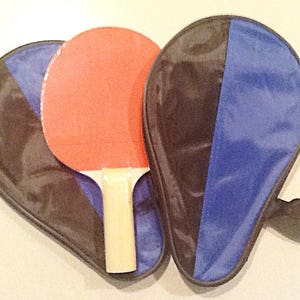 May include: A red and black ping pong paddle set with a black and blue carrying case.