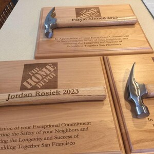 May include: Three wooden plaques with a hammer and The Home Depot logo. Each plaque has a name and the year 2023. The text reads "In Appreciation of your Exceptional Commitment to Supporting the Safety of your Neighbors and Ensuring the Longevity and Success of Rebuilding Together San Francisco."