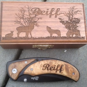 May include: A wooden box with a hinged lid and a brass latch. The box has an engraved design of a deer, a wolf, and a bear. The box is engraved with the name 'Reiff'. A black folding knife with a wooden handle is also pictured. The knife handle is engraved with the name 'Reiff'.