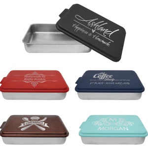 May include: Set of four 9x13 inch silver baking pans with lids. The lids are personalized with different designs and text, including "Ashland Happiness is Homemade", "Homemade by Kathy Bozden", "The Coffee Shop 1st Place Annie Wayland", and "M Morgan".