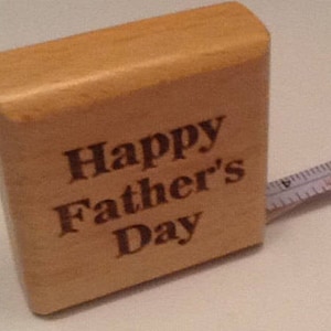 May include: A wooden tape measure with the words "Happy Father's Day" engraved on the front.