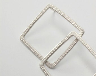 Geometric earrings with texture and square shape in silver.