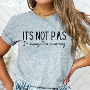 Könnte beinhalten: Ein graues T-Shirt mit dem Aufdruck "IT'S NOT P.M.S. I'm always this charming".