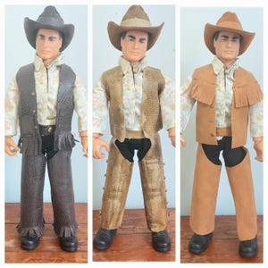 May include: Three action figures dressed as cowboys, each wearing a hat, a floral print shirt, a vest, and chaps over black pants. The first figure wears dark brown textured gear, the second tan textured gear, and the third smooth tan suede-like gear.