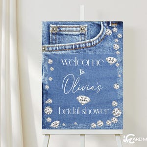 May include: A blue denim bridal shower welcome sign with rhinestones and the text "Welcome to Olivia's Bridal Shower".