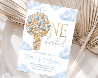 Può includere: Un invito di compleanno blu e oro con un orsacchiotto in un pallone aerostatico fatto di palloncini. L'invito dice "Isn't he one derful" e "Mattie's First Birthday".