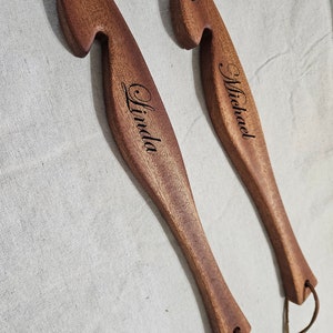 May include: Two wooden crochet hooks with leather loops. The hooks are engraved with the names "Linda" and "Michael".