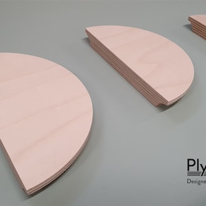 Könnte beinhalten: Drei halbkreisförmige Holzregale in verschiedenen Größen. Die Regale sind aus hellem Holz gefertigt und haben eine glatte Oberfläche. Ply-Works Entworfen und hergestellt in Glasgow.