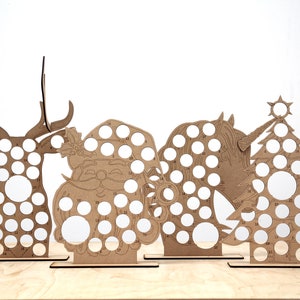 May include: Four wooden Christmas countdown advent calendars, each featuring a different design: a reindeer, Santa Claus, a unicorn, and a Christmas tree. Each design has 24 numbered circles for placing treats or small gifts.