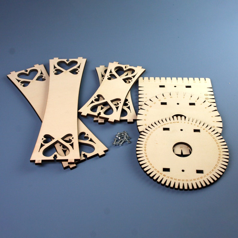 May include: A wooden kit for making a jewelry stand. The kit includes four pieces of wood with heart-shaped cutouts, a circular ruler with numbers, and a square ruler with numbers. The kit also includes small screws.