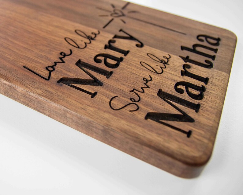 May include: A wooden cutting board with the text "Love like Mary, Serve like Martha" engraved on it.