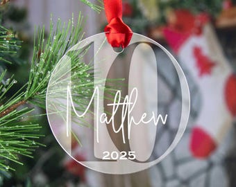 May include: Clear acrylic Christmas ornament with the number 10, the name Matthew, and the year 2025 printed in white.
