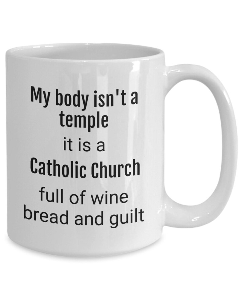 May include: White ceramic coffee mug with black text that reads "My body isn't a temple it is a Catholic Church full of wine bread and guilt"