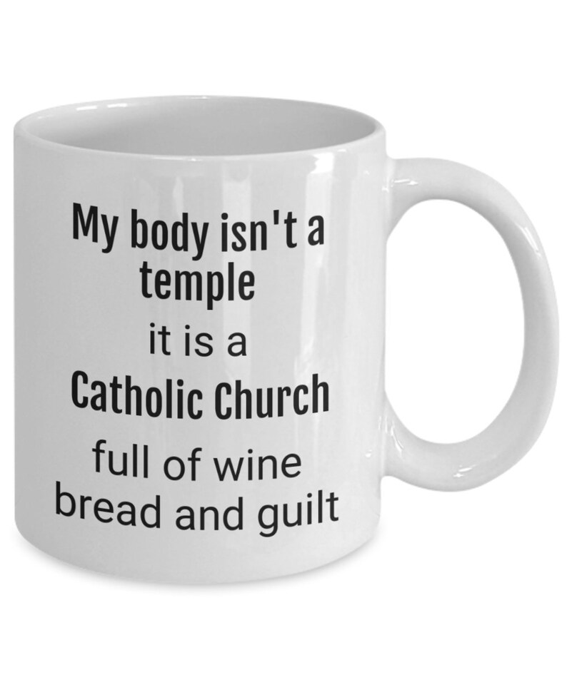 May include: White ceramic coffee mug with black text that reads "My body isn't a temple it is a Catholic Church full of wine bread and guilt"