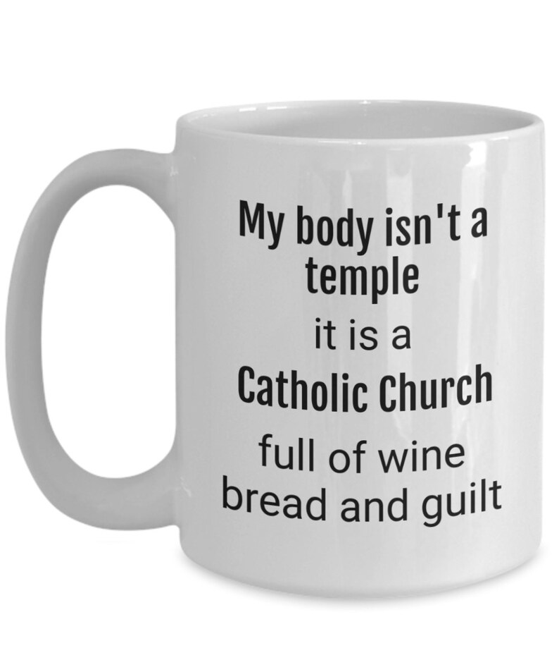 May include: White ceramic coffee mug with black text that reads "My body isn't a temple it is a Catholic Church full of wine bread and guilt"